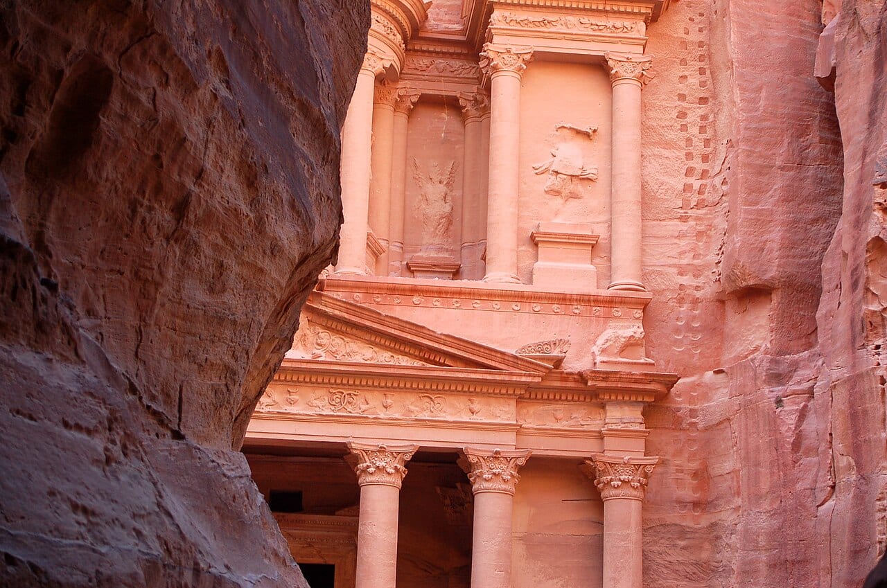 The carved facade of the Treasury framed by the dark walls of the Siq