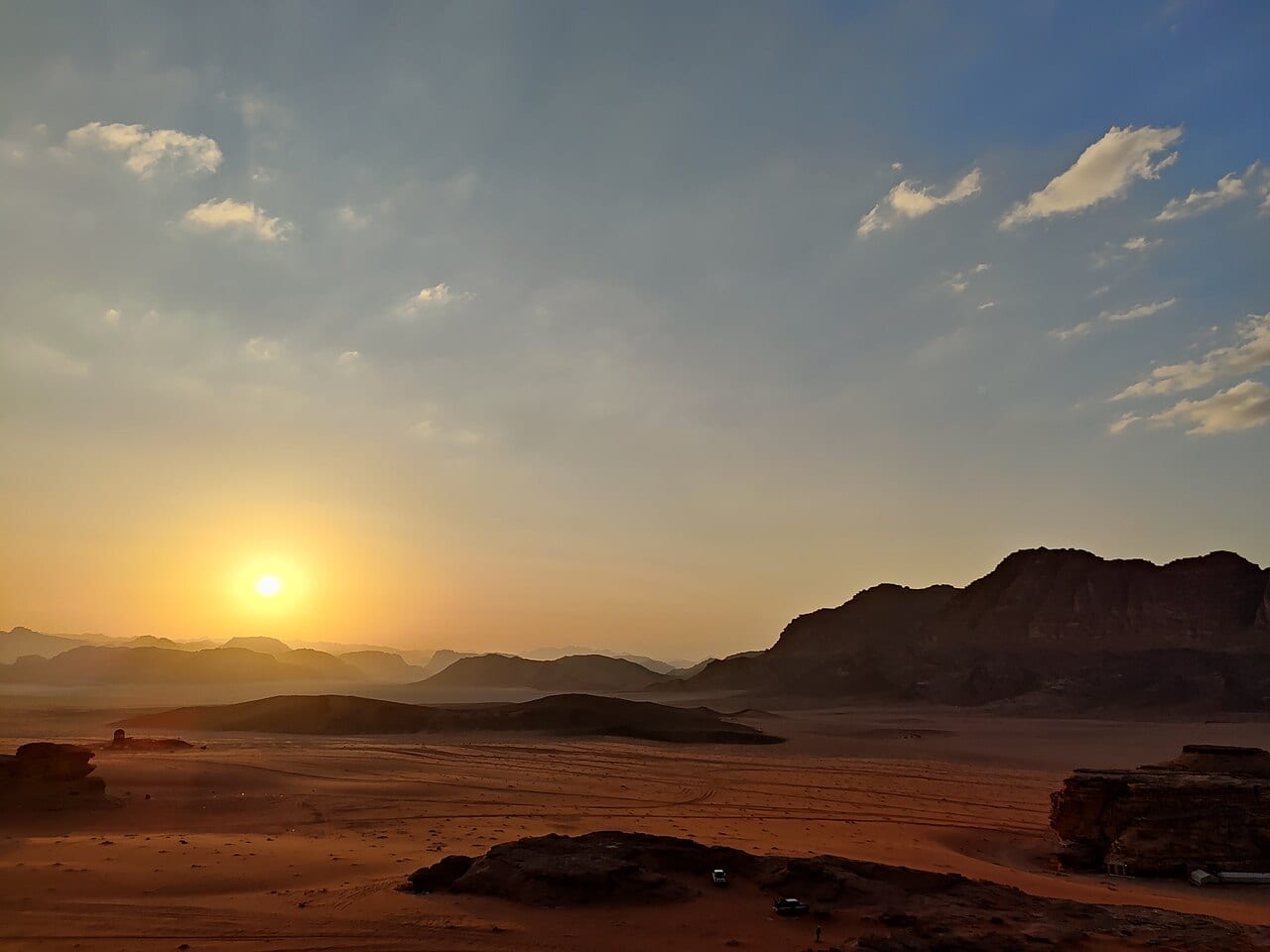 The sun setting behind rock formations in the Wadi Rum desert