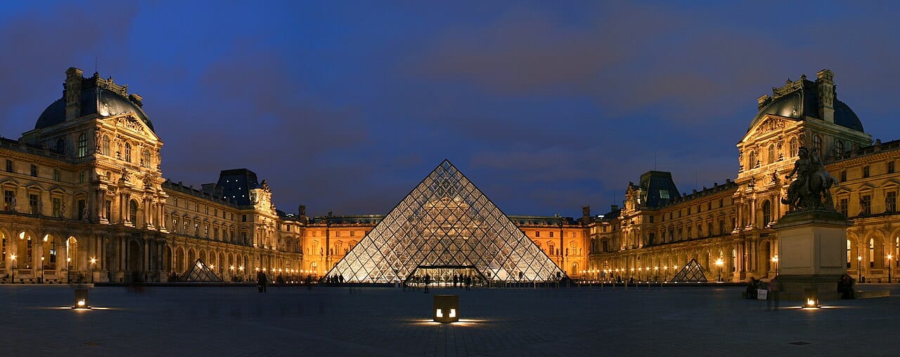 The Louvre Museum courtyard and glass pyramid at night in Paris