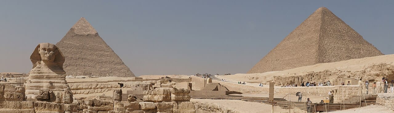 The three pyramids of Giza with visitors and camels in the foreground