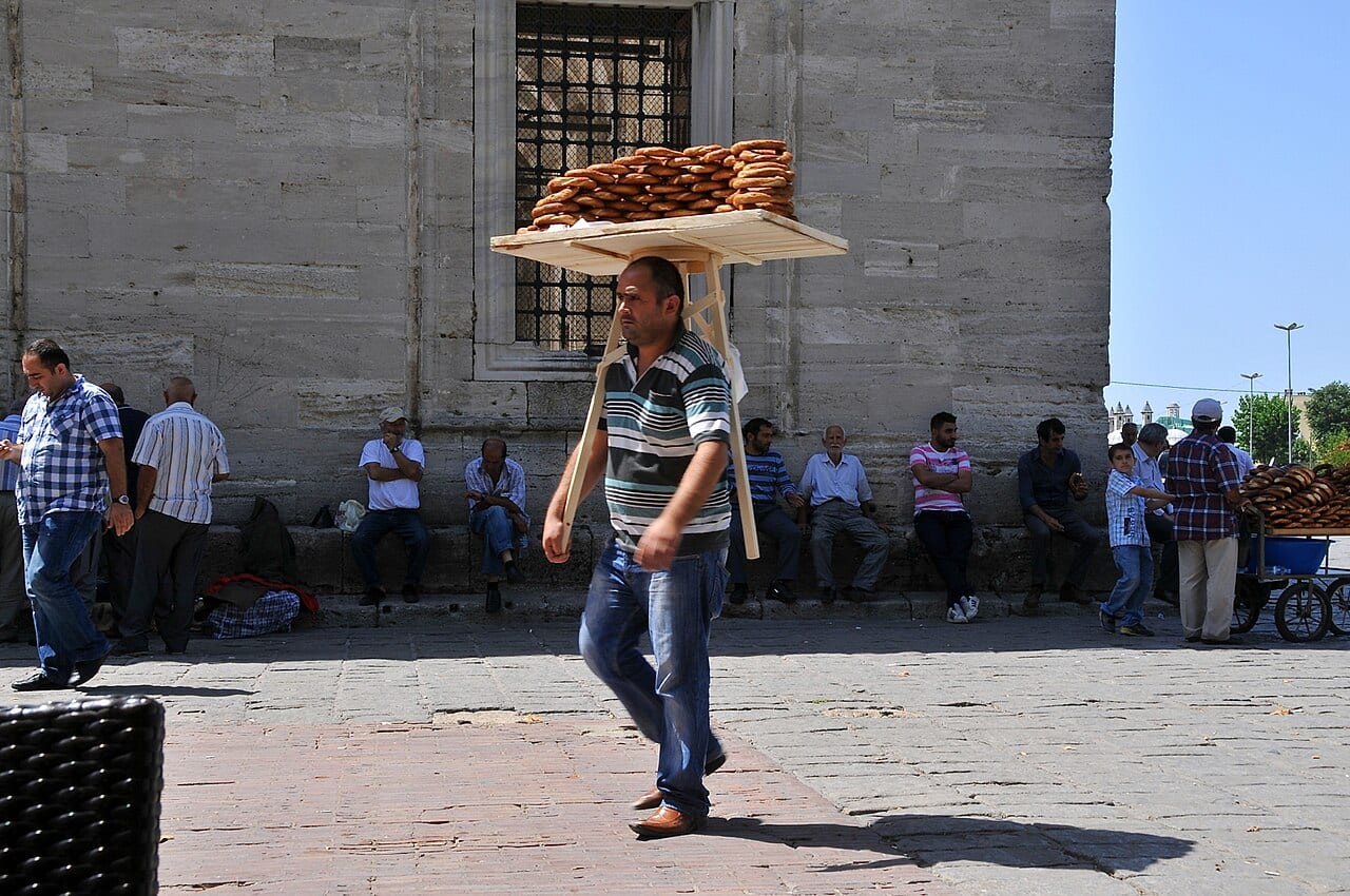 A street seller carrying a tray of simit sesame bread rings on his head
