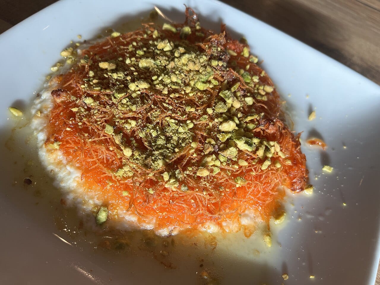 A tray of knafeh with melted cheese and orange crust