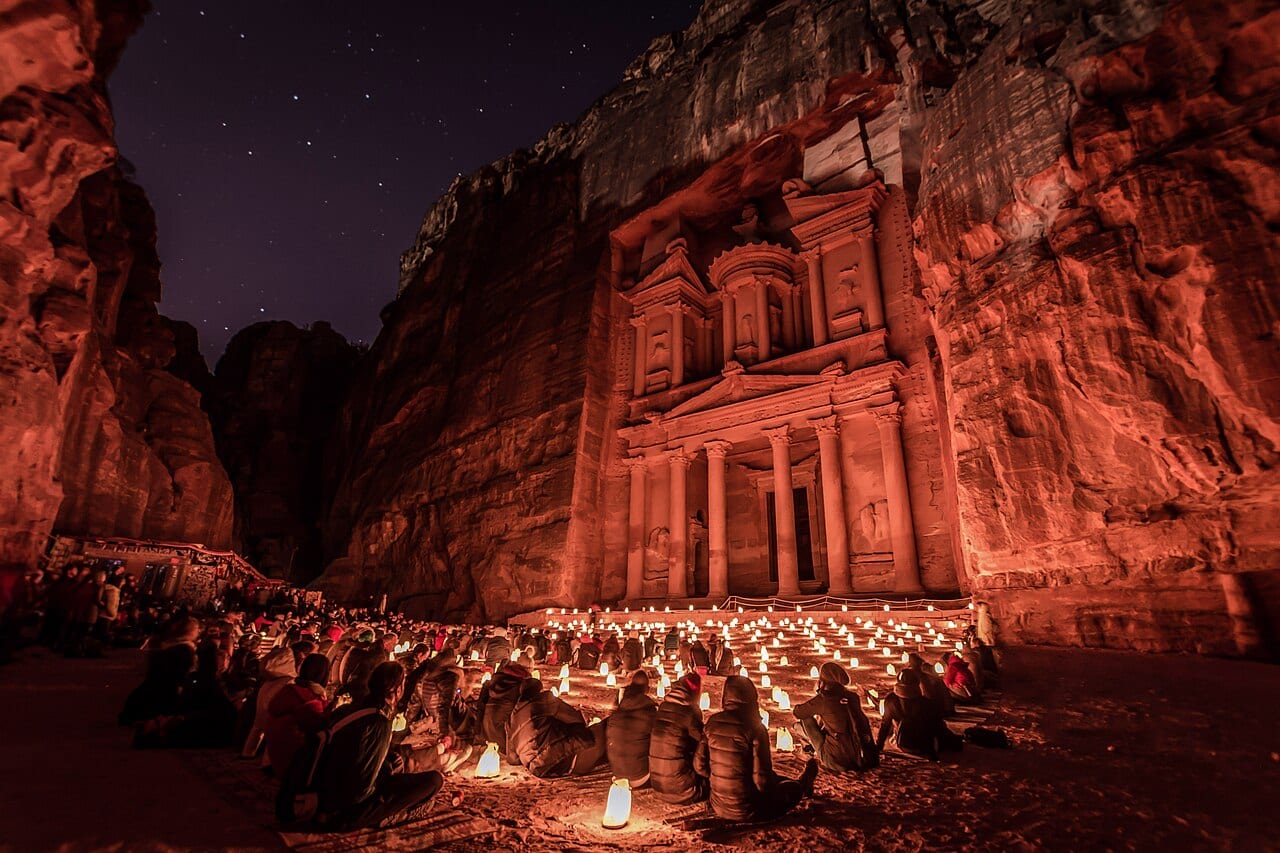 The Treasury at Petra lit by rows of candles at night with visitors seated in front