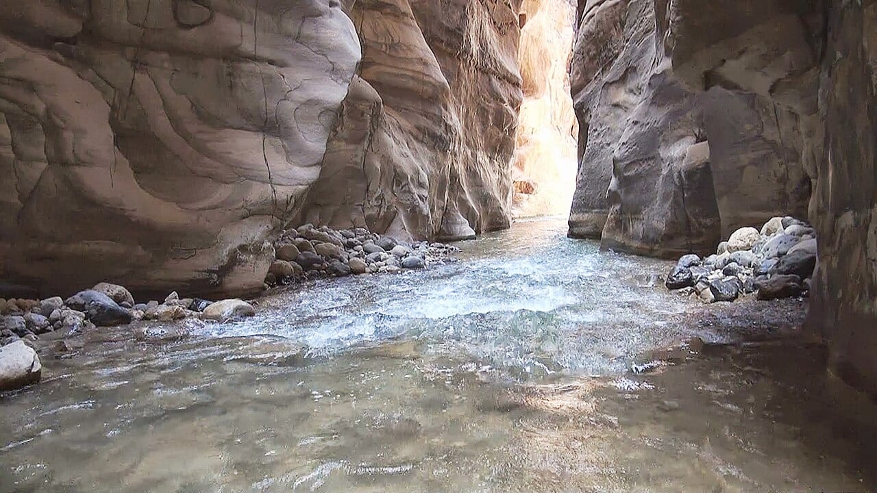 Hikers wading through the narrow canyon of the Wadi Mujib Siq Trail
