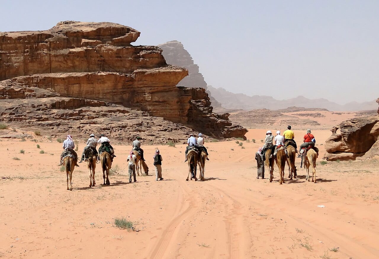 A group of travellers riding camels through the Wadi Rum desert