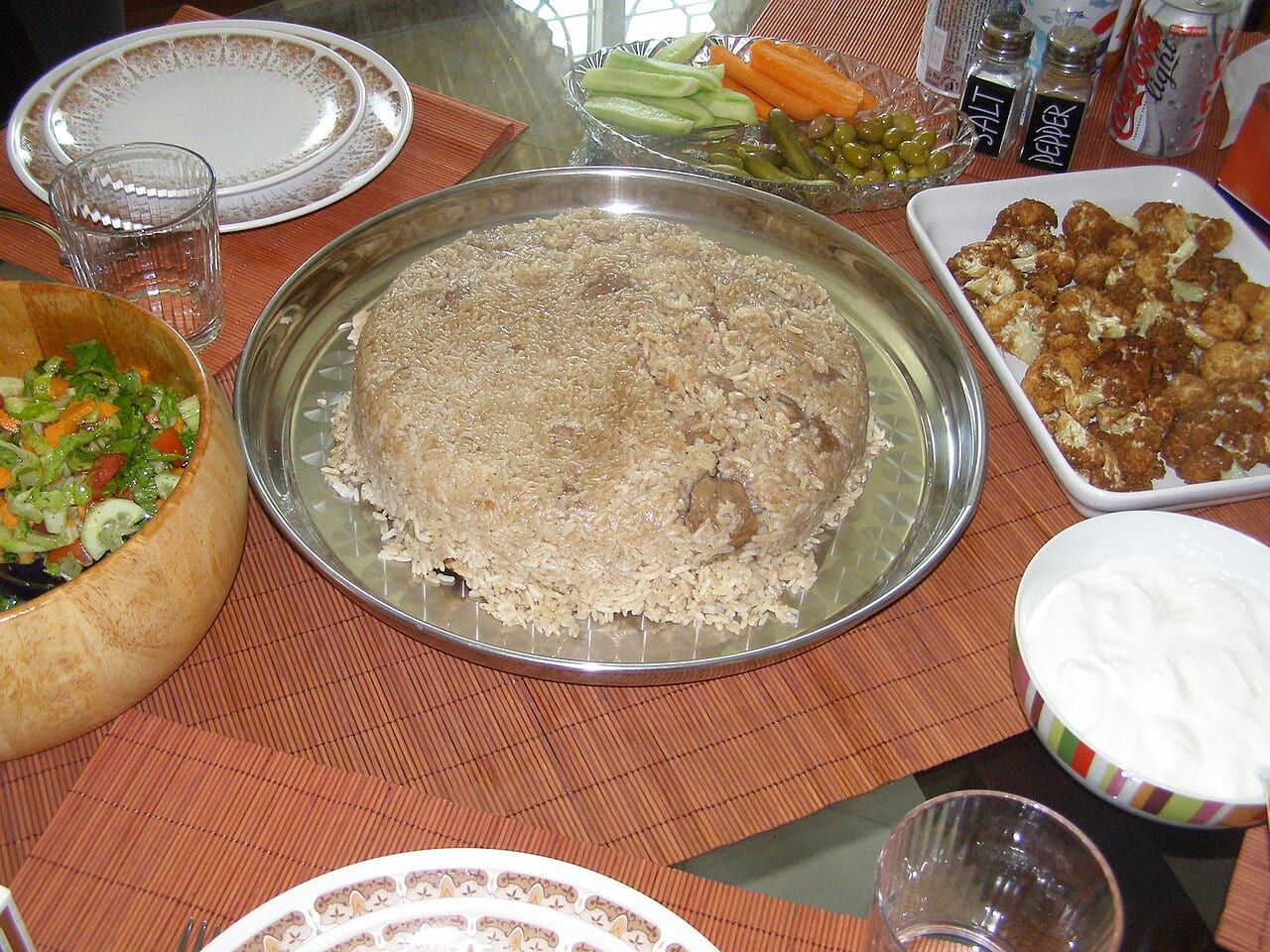 Maqluba, an upside-down pot of rice, vegetables and meat, served with yoghurt and salad